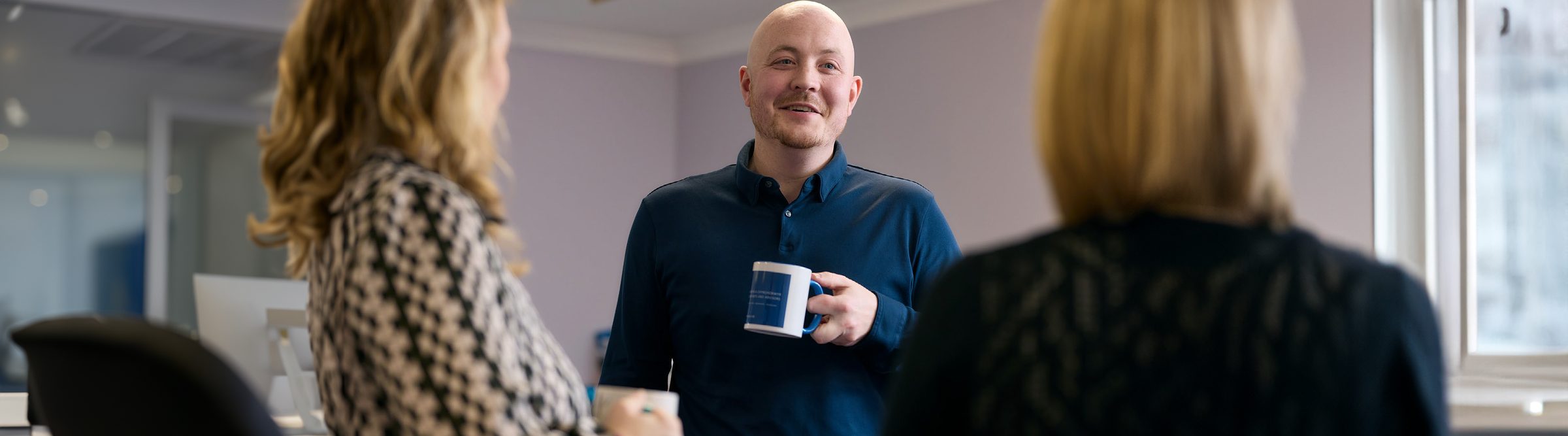 Members of the PJE team chatting over coffee in the office